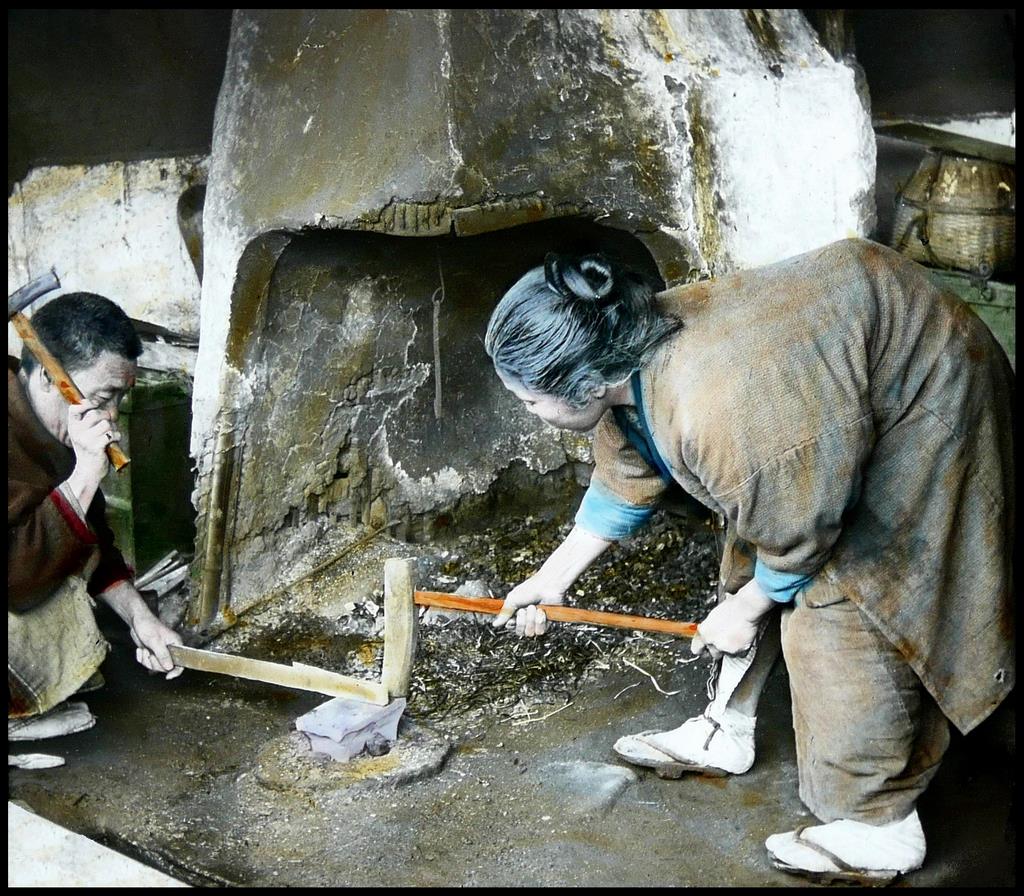 A blacksmith and his wife forge a blade, ca. 1904-05. Hand-tinted glass lantern slide printed from a half-stereoview negative. (Courtesy of Okinawa Soba)